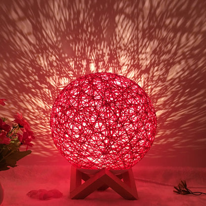 Spherical hand-knitted rattan table lamp with remote control on a wooden desk