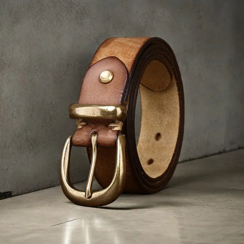 Men's black genuine cattlehide leather belt with a copper pin buckle on a jeans background.