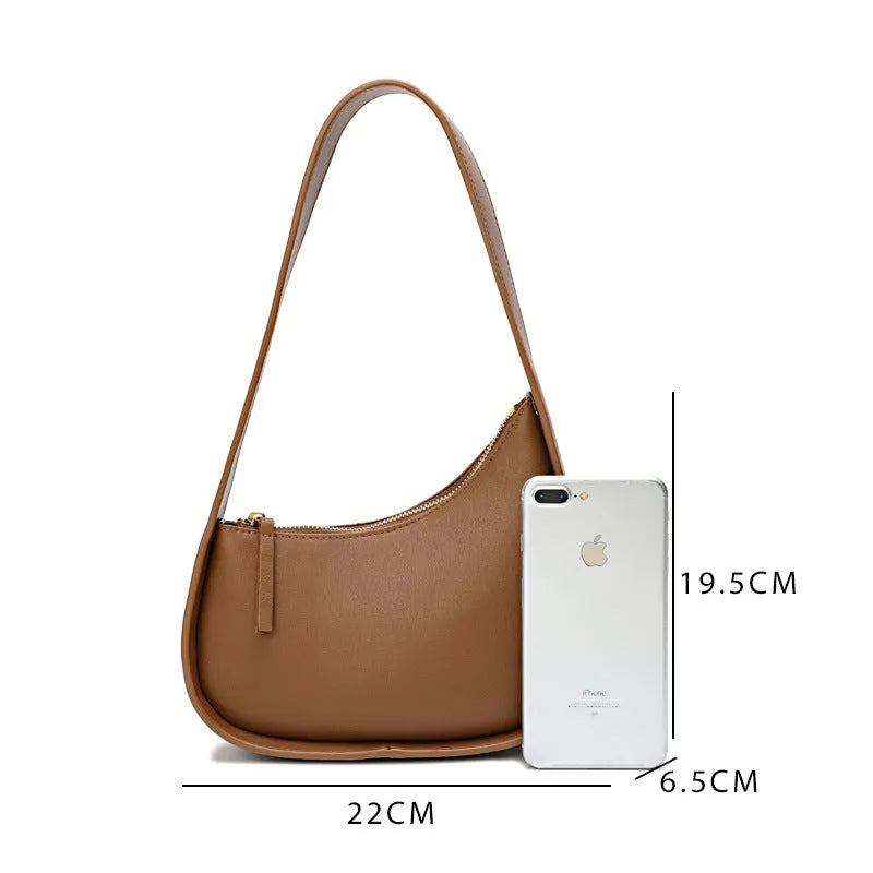 Structured caramel half-moon leather women's shoulder bag with a wide adjustable strap and zip closure.