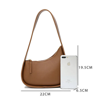 Structured caramel half-moon leather women's shoulder bag with a wide adjustable strap and zip closure.