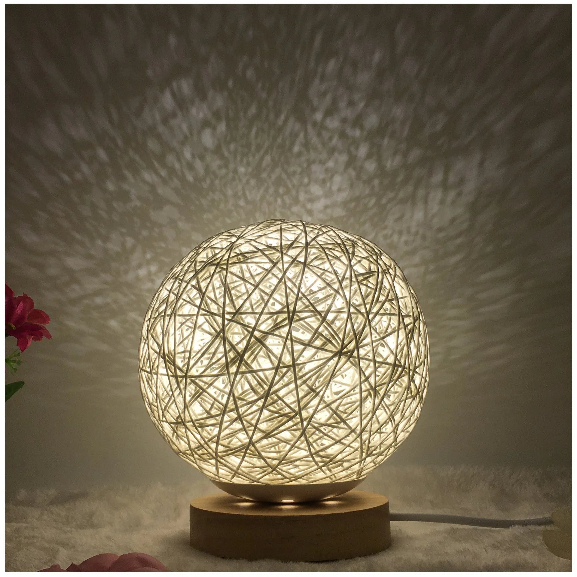 Spherical hand-knitted rattan table lamp with remote control on a wooden desk