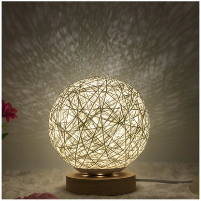 Spherical hand-knitted rattan table lamp with remote control on a wooden desk