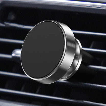 Magnetic car phone holder with aluminium alloy CD-textured base attached to a car air vent, holding a smartphone.