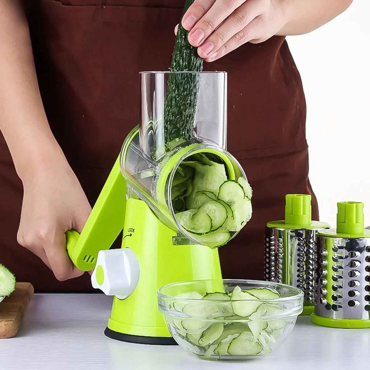 Round mandoline vegetable slicer with three stainless steel blades and a rubber suction base, in blue green colour.