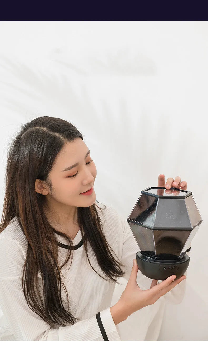 Children's rotating star night light projecting coloured starlight patterns on a bedroom wall.