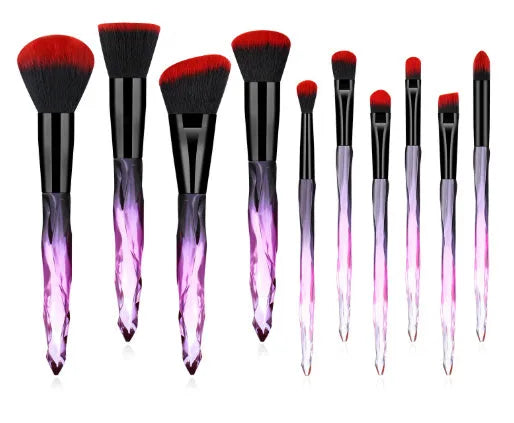 Ten clear crystal-handled foundation brushes with black synthetic bristles laid out on a surface.