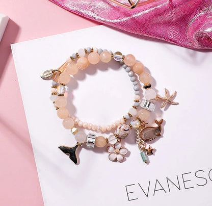 Elegant whale tail bracelet in vibrant colors with flower and starfish accents, perfect for adding a touch of coastal charm to any outfit.