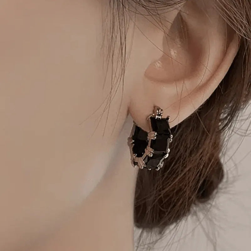 A pair of geometric U-shaped copper earrings with a round zircon stone in a gold-coloured setting.