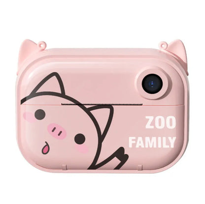 Pink instant print digital camera with LCD screen on a table next to printed photos and accessories.