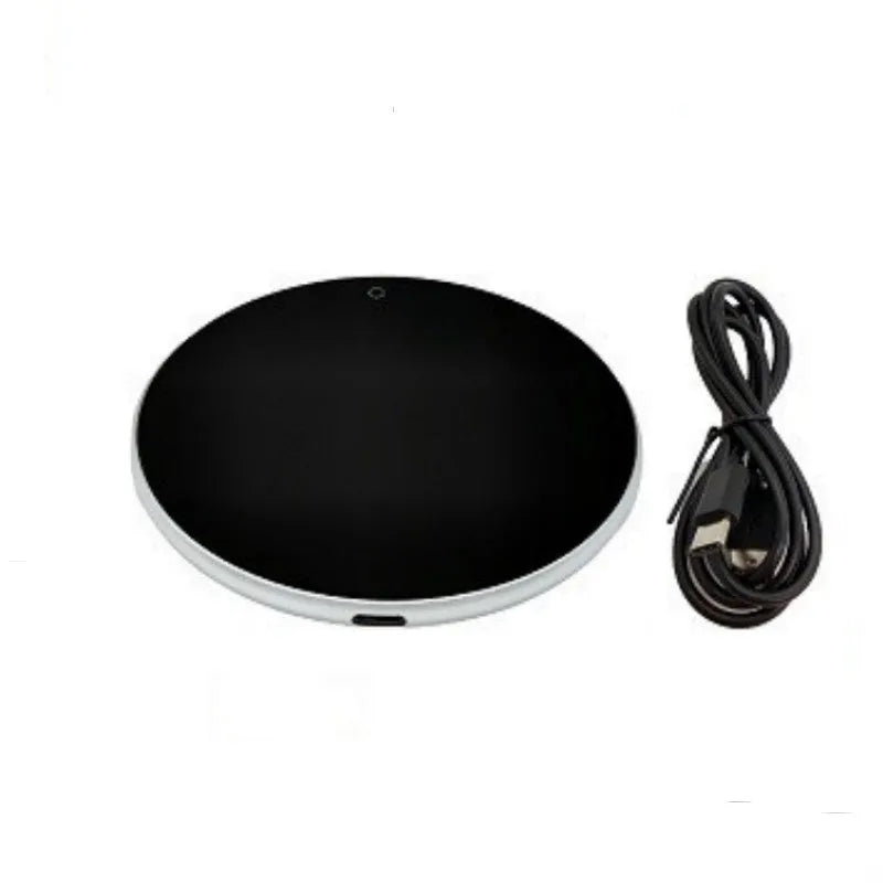 Black USB heating coaster on a desk next to a coffee mug, showing touch controls and coloured indicator light.