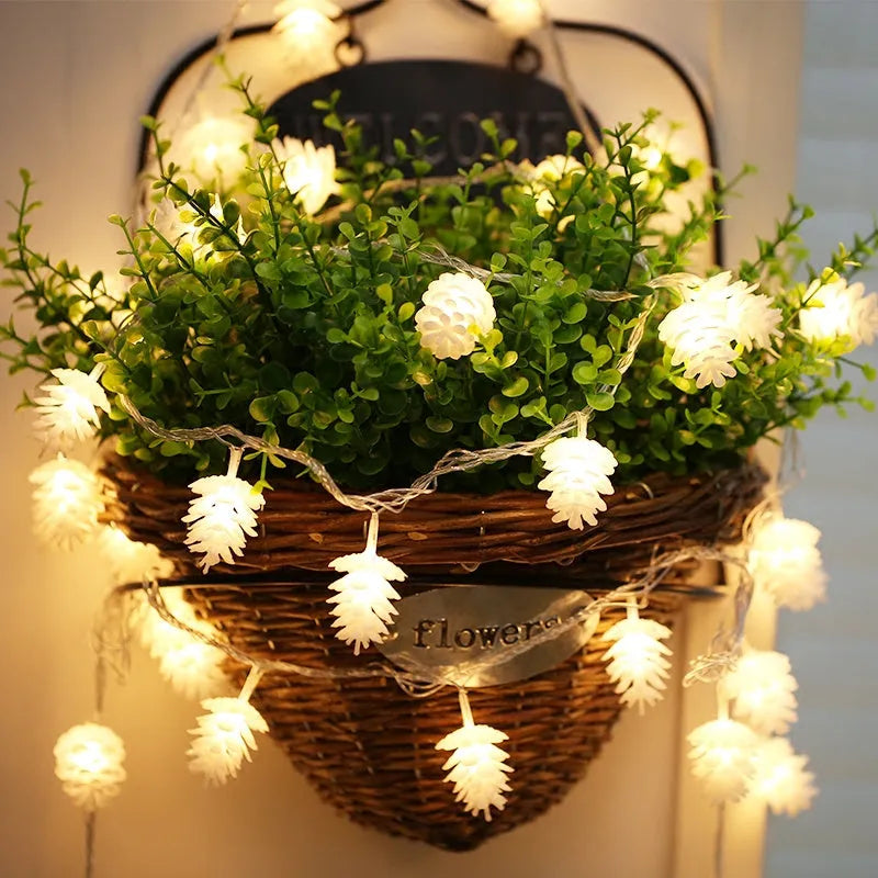 Warm white LED pine cone fairy light string on a green backdrop, showing plastic shell details.