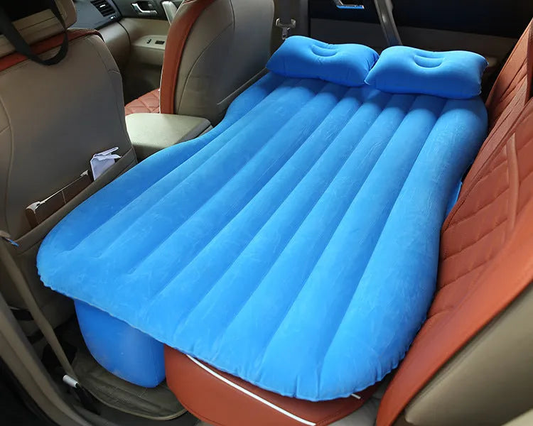Black inflatable car bed with flocked surface and two pillows, shown folded into a chair inside a vehicle.