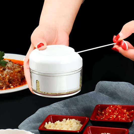 White manual food chopper with stainless steel blades on a kitchen countertop.