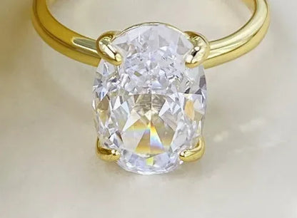 Oval silver ring with four-prong setting and a hand-cut stone on a finger.