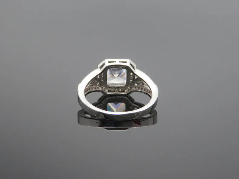 Geometric platinum-coloured copper ring with an inlaid zircon stone, showing its hollow quadrilateral design.