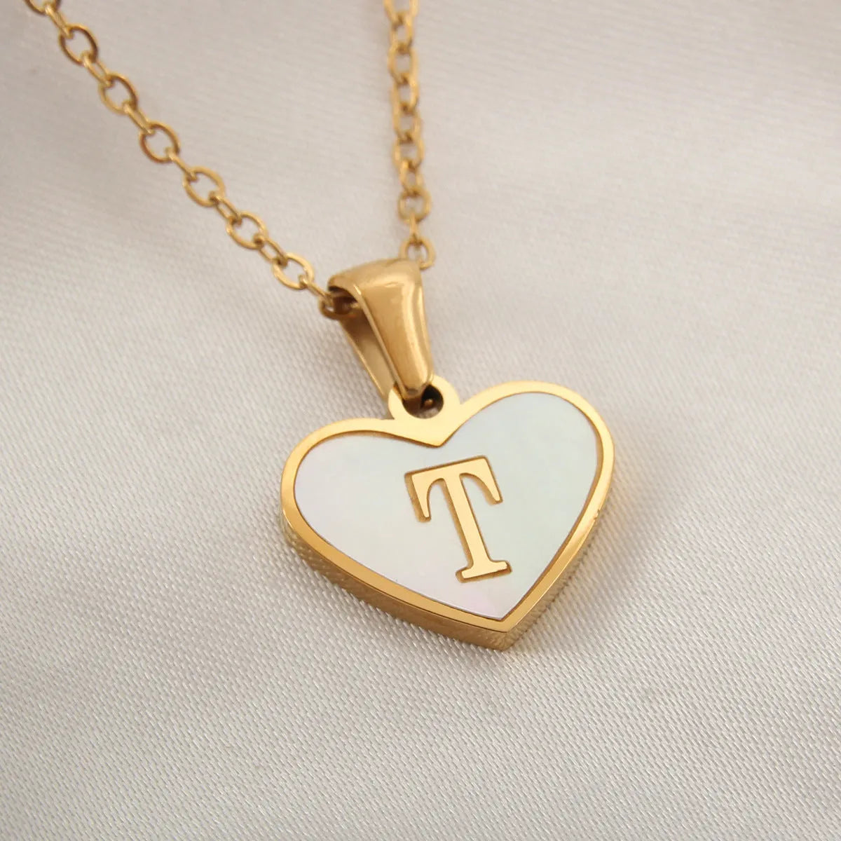 Gold-plated clavicle necklace with a white shell heart pendant, personalised with a letter from A to Z.