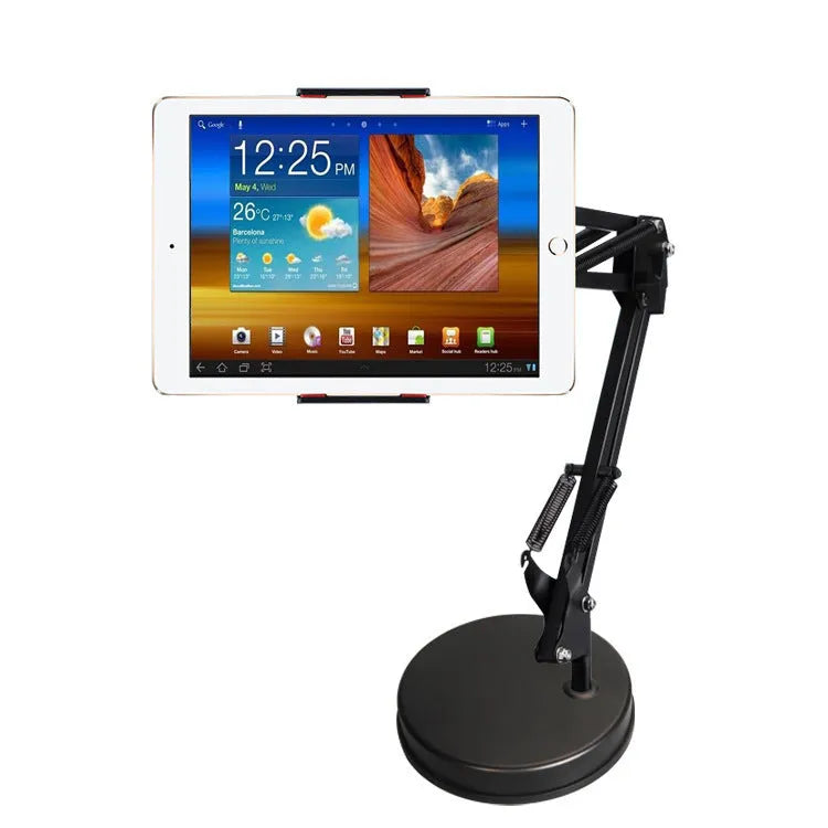 Black universal phone stand with long metal arm and heavy round base on a wooden desk