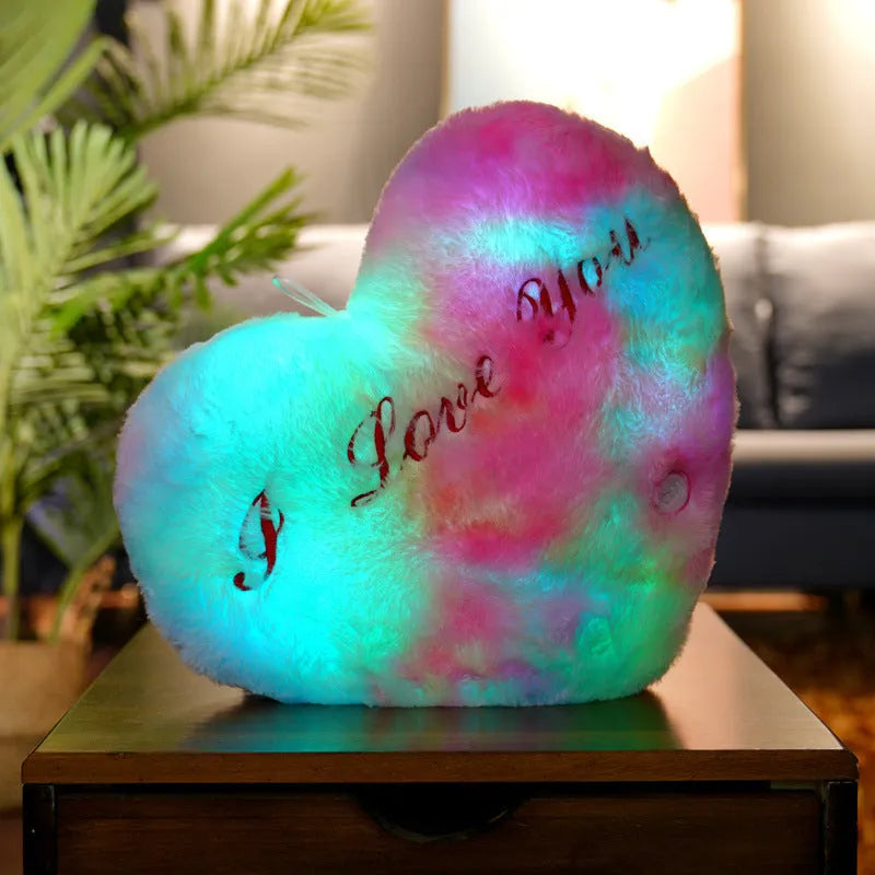 Colourful glowing five-pointed star plush pillow on a dark background.
