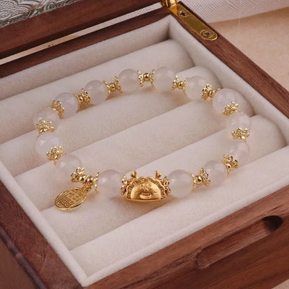 A women's glass glazed bracelet with floral and zodiac animal charms in red, pink, and white pearl beads.