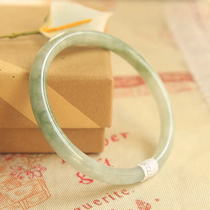 Green geometric jade waxy bracelet on a wrist, showing its 10mm thickness and Chinese style.