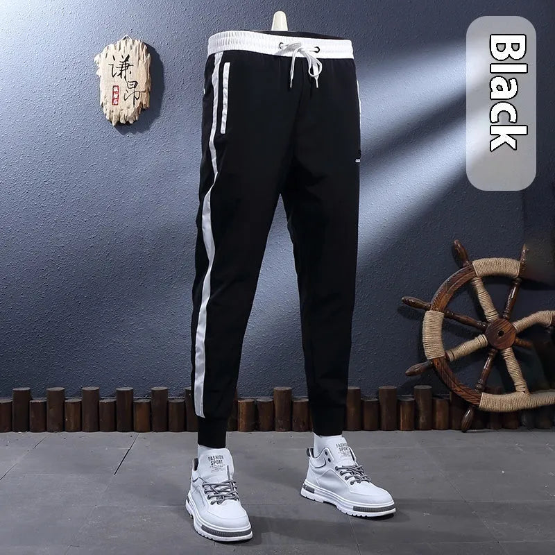 Men's ice silk skinny sports pants in black or white with striped tapered leg and ankle-tied hem
