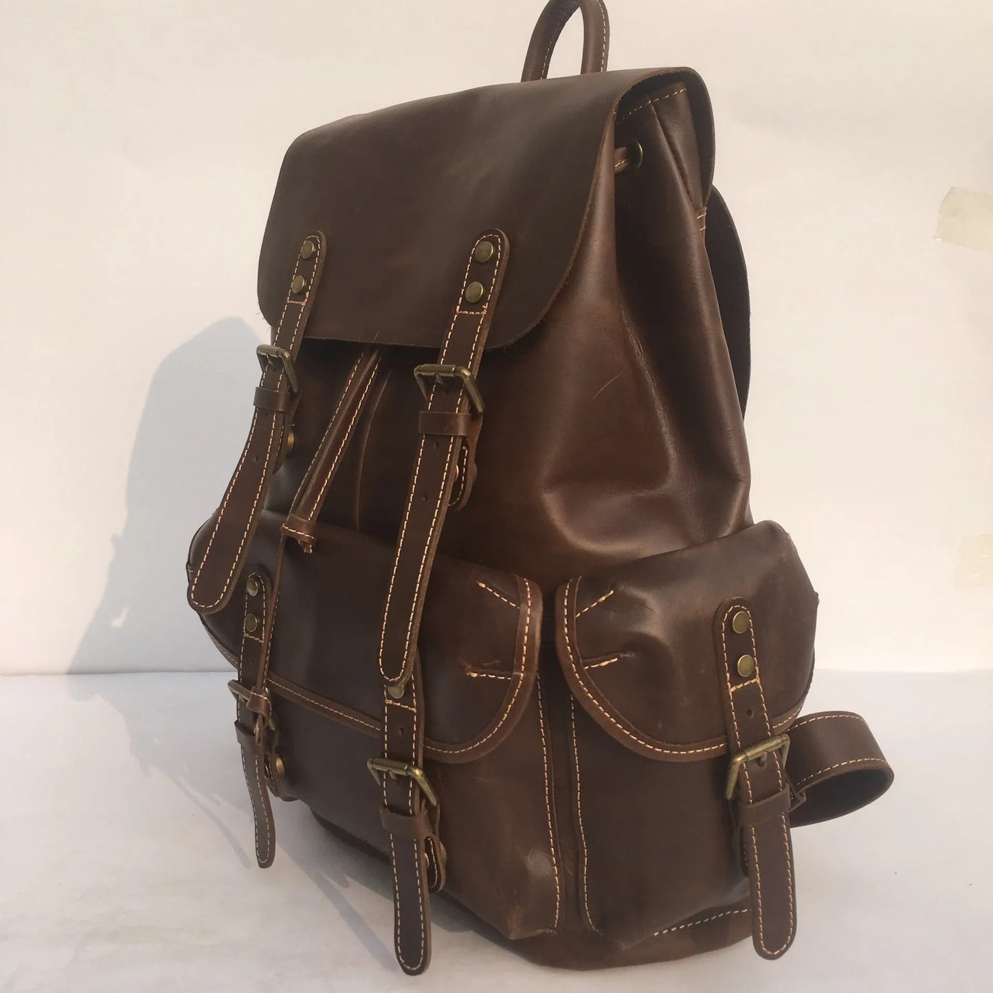 Men's brown leather backpack showing cowhide texture and air pillow belt system