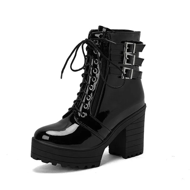 Women's black chunky heel ankle boots with round toe and front lace-up design on a wooden floor.