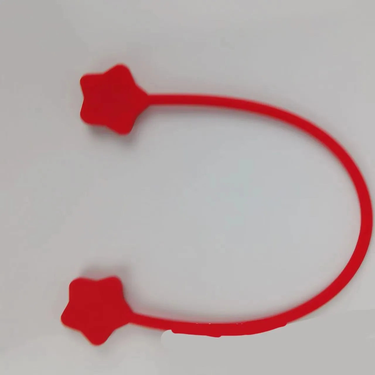 Compact purple silicone cable winder with magnet, shown coiling a white headphone cable.