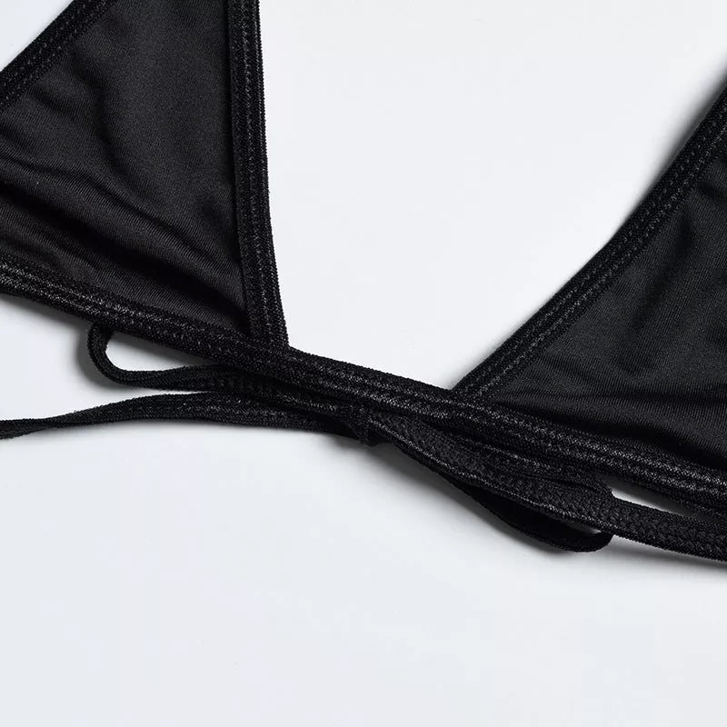 Solid black sling bikini set for women, includes bra, jacket, skirt, and shorts