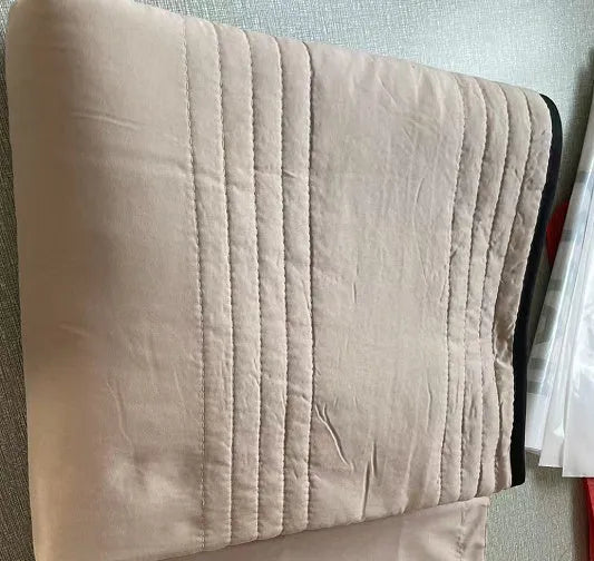 Lightweight plain coloured polyester summer quilt on a bed