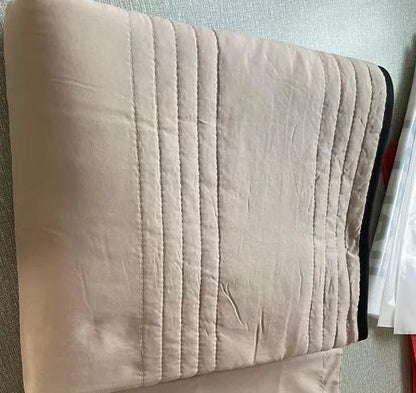 Lightweight plain coloured polyester summer quilt on a bed
