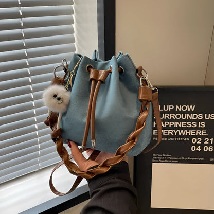 Blue synthetic leather cross body bucket bag with adjustable strap and optional hanging ornaments