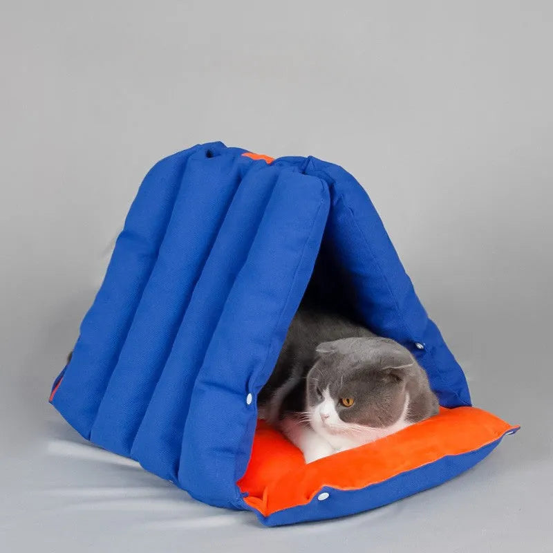 Blue triangular cotton cat bed with a removable cover on a wooden floor.