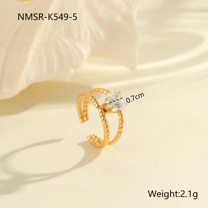 Gold electroplated stainless steel open mouth ring with geometric shapes and zircon inlay on a heart drop.