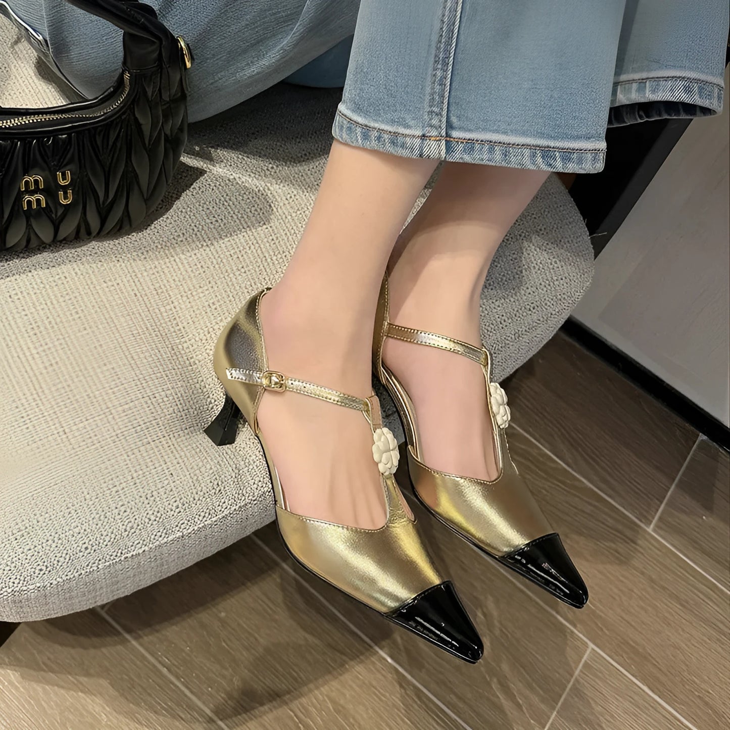 Women's black pointed toe stiletto heel shoes with floral buckle on sheepskin upper.