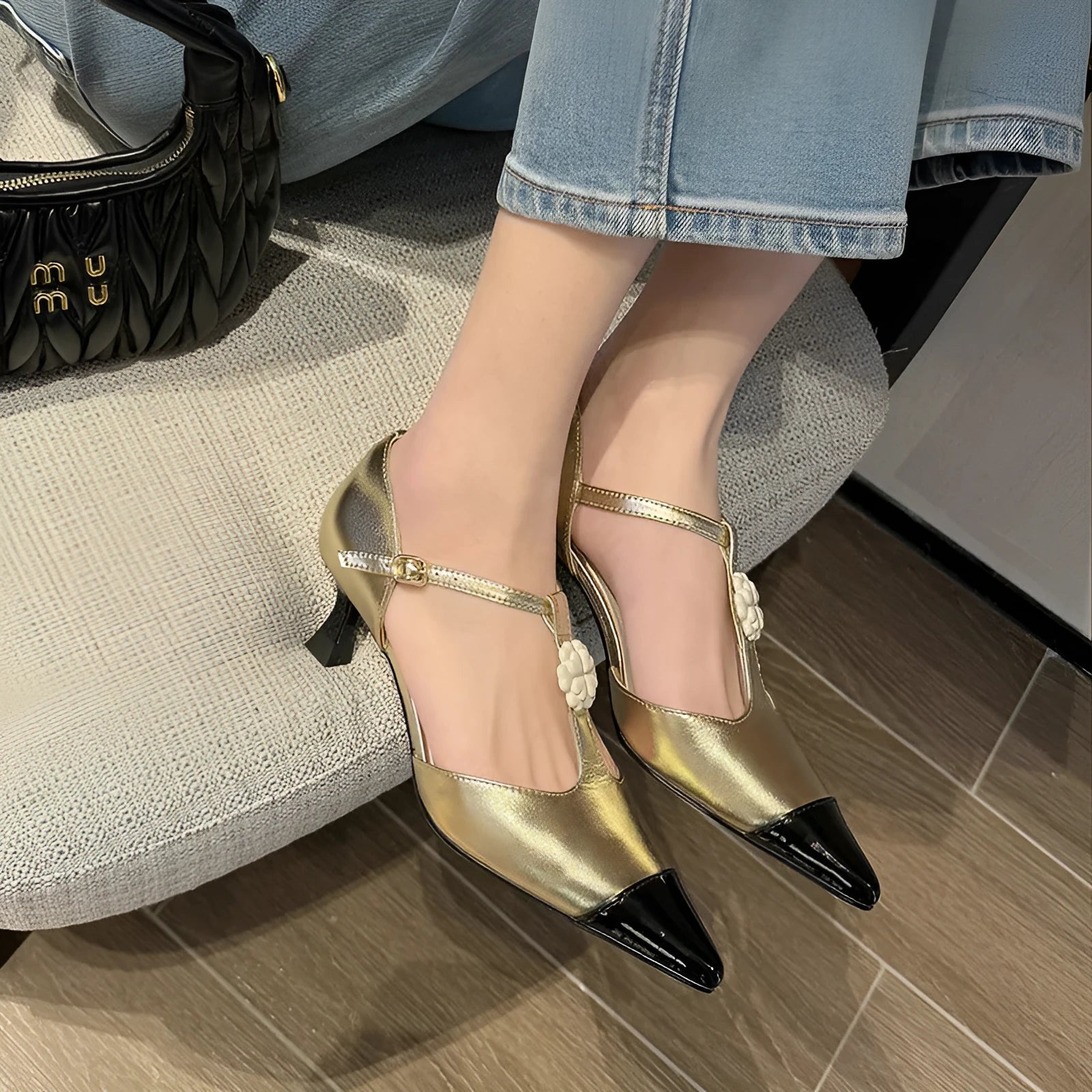 Women's black pointed toe stiletto heel shoes with floral buckle on sheepskin upper.