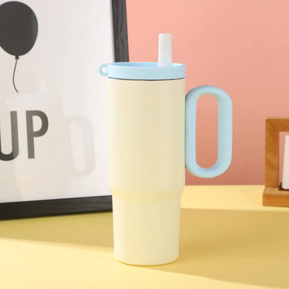 Large pink insulated straw cup with a black handle and push-button lid on a wooden table
