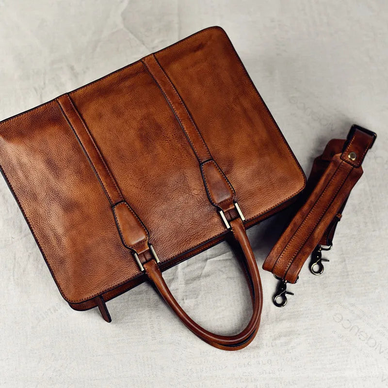Men's khaki retro leather handbag with horizontal square shape and zipper top, shown on a desk.