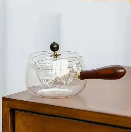Glass teapot with wooden handle showing transparent borosilicate construction and removable infuser