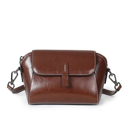 Women's brown shell-shaped genuine leather messenger bag with a single shoulder strap and visible stitching.