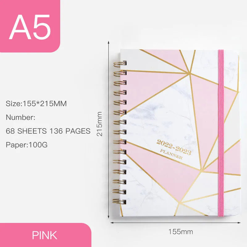 A5 spiral coil notebook open showing annual calendar pages and spiral binding