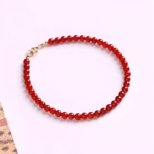 Slim red agate bead bracelet for women on a wrist, classic minimalist jewellery style.