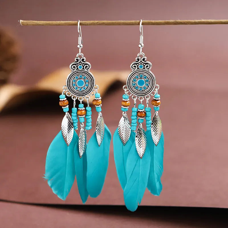 Bohemian feather leaf pattern alloy earrings in round drop shape on a colour selection background.