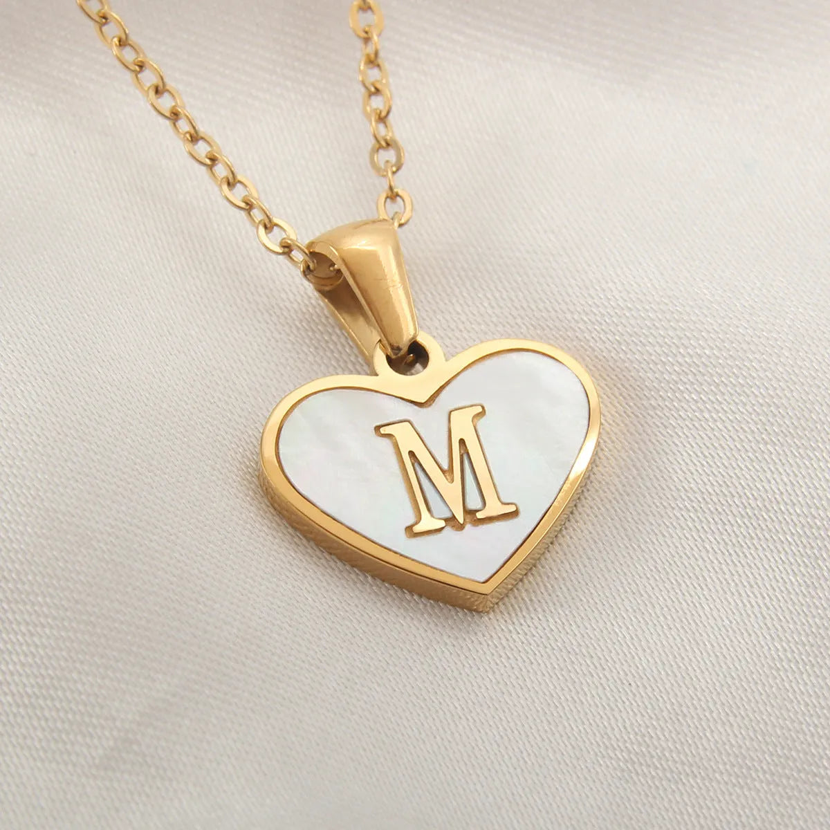 Gold-plated clavicle necklace with a white shell heart pendant, personalised with a letter from A to Z.