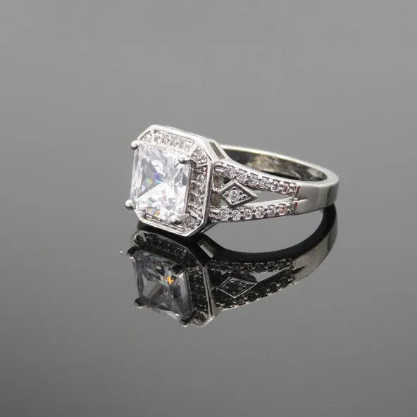 Geometric platinum-coloured copper ring with an inlaid zircon stone, showing its hollow quadrilateral design.