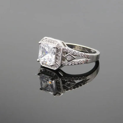Geometric platinum-coloured copper ring with an inlaid zircon stone, showing its hollow quadrilateral design.