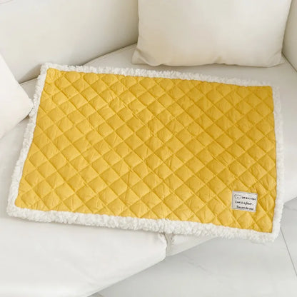 Quilted terry cloth pet blanket for cats in blue, grey, pink, or yellow colour on a pet bed.