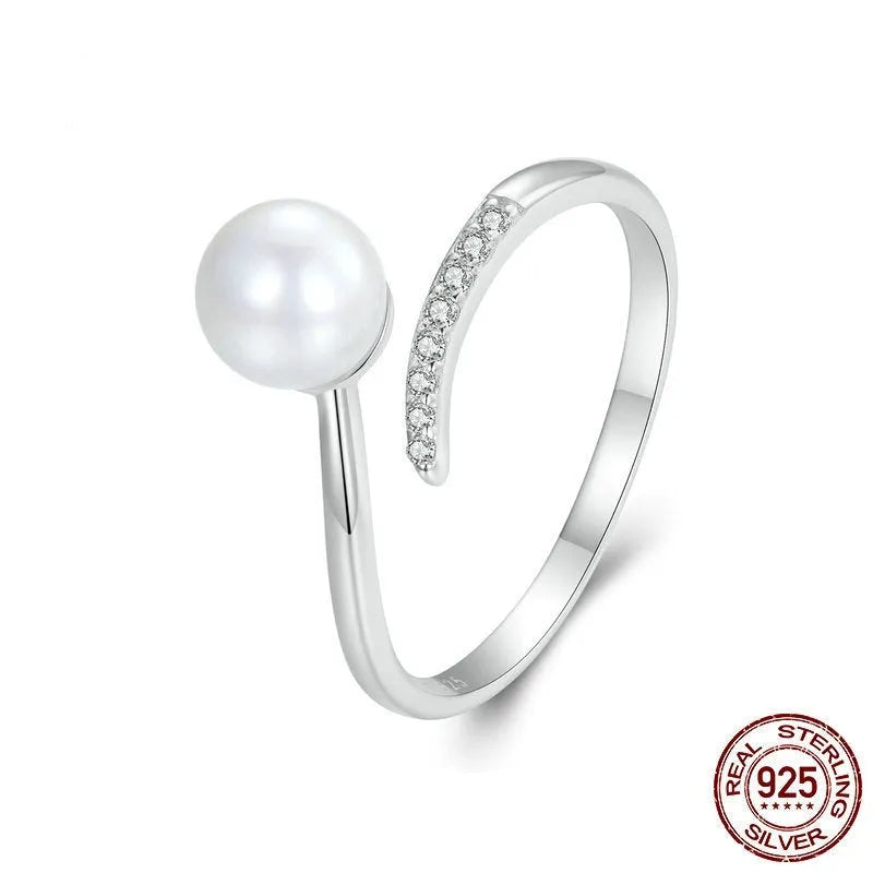 Silver adjustable open ring with white shell pearls on a white background.