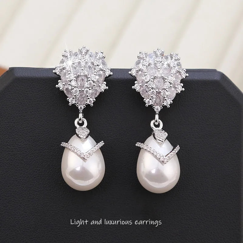 Women's drop-shaped freshwater pearl earrings with zircon inlay on 18K gold-plated settings.