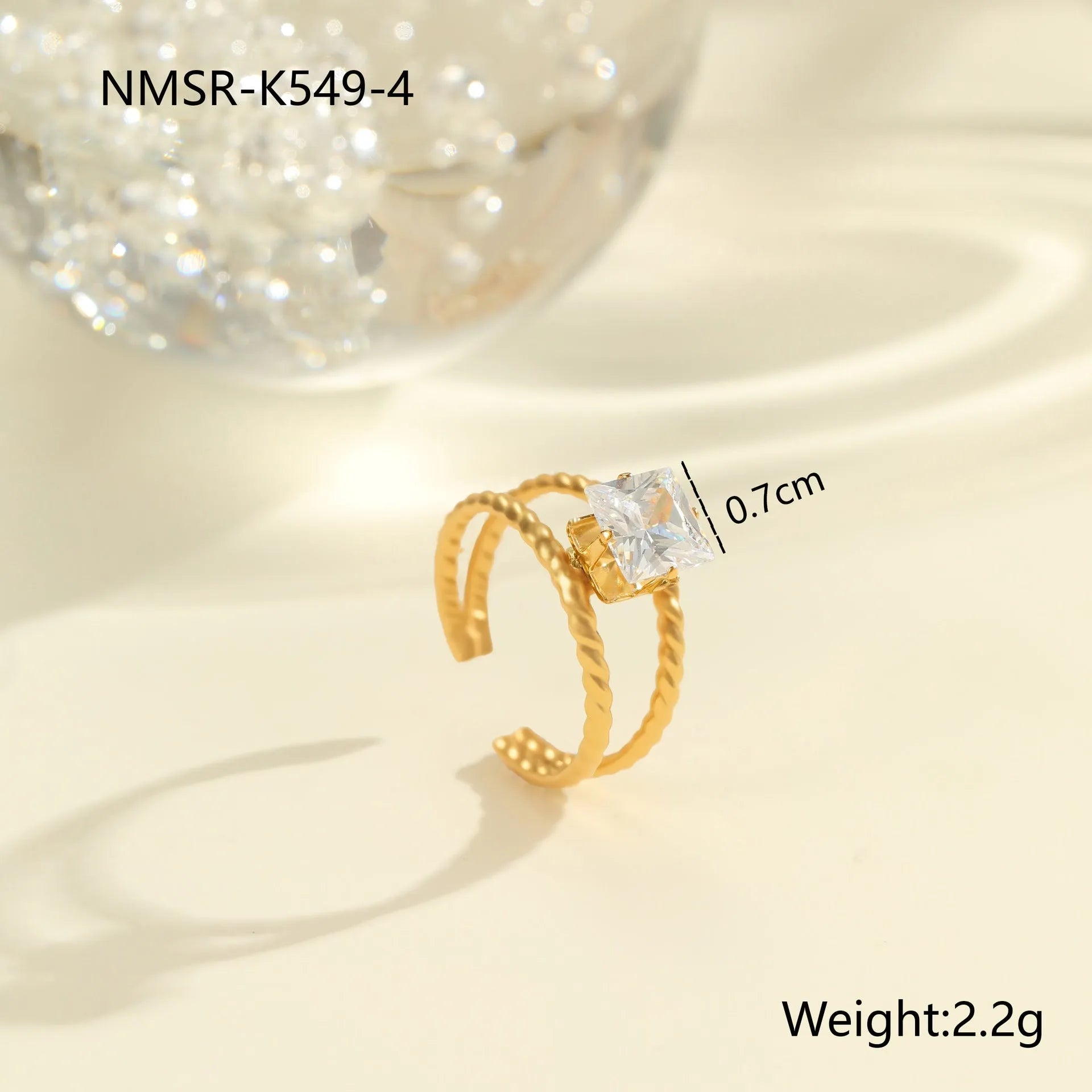 Gold electroplated stainless steel open mouth ring with geometric shapes and zircon inlay on a heart drop.
